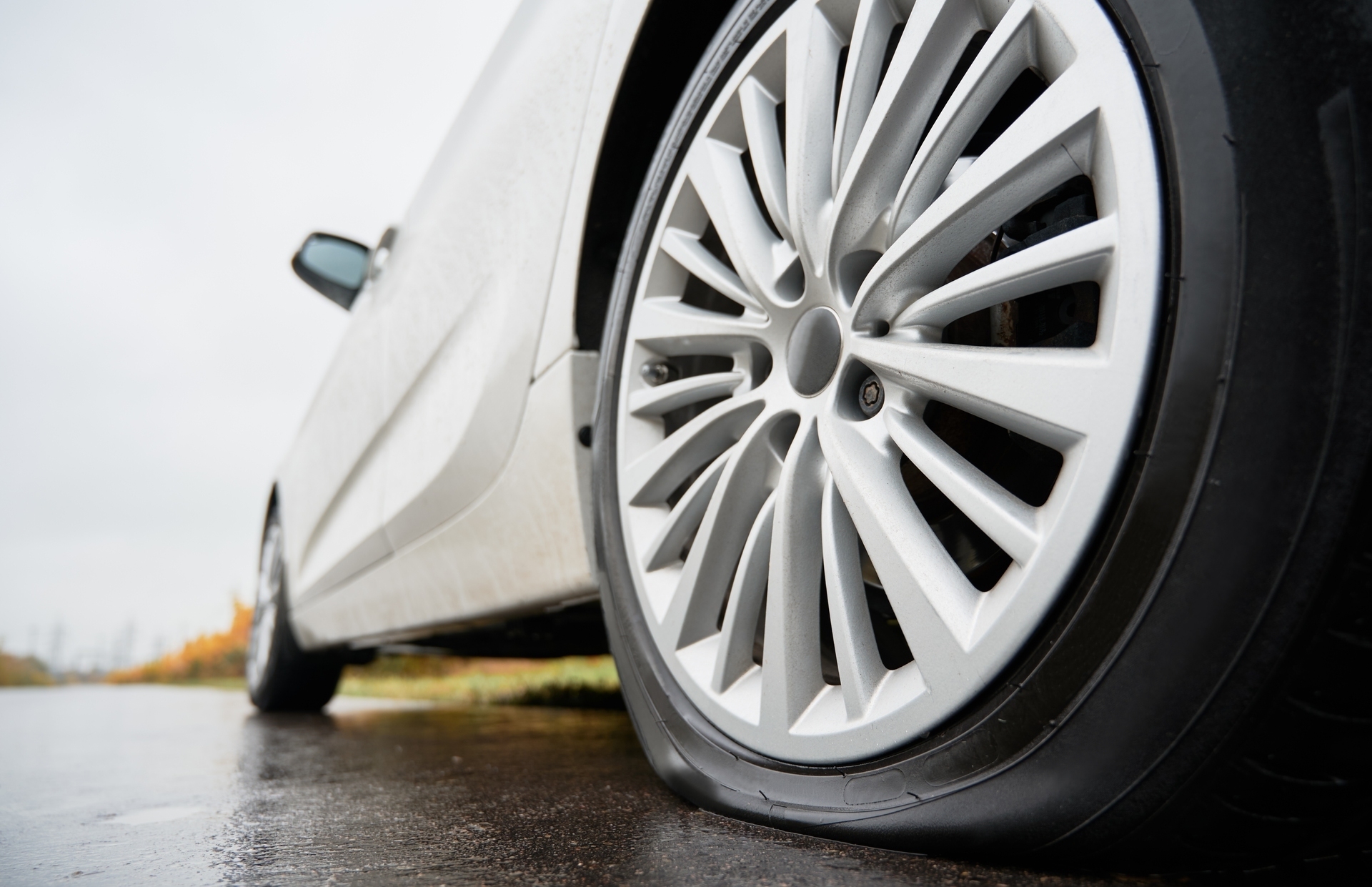 stopped-white-car-with-punctured-car-tire-roadside